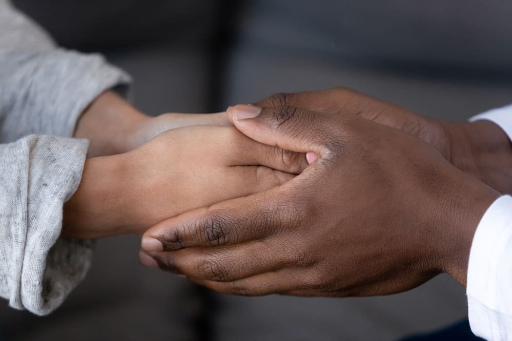 Two hands clasped together, one of them holding a hand.